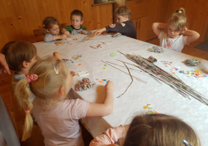 Dzieci ozdabiają serduszka z wikliny gazetowej.