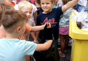 Dzieci z grupy Pand zebrały worek papierów i plastiku i segregują je do koszy