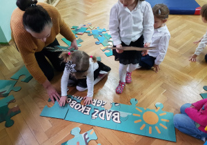Dziewczynki z grupy Żabki układają ekologiczne puzzle.