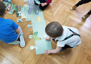 Chłopcy z grupy Żabki układają ekologiczne puzzle.