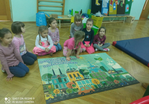 Dziewczynki z grupy Małpki prezetują swój obrazek z puzzli - ekologiczne miasto..