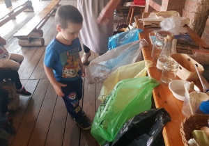 Chłopiec segreguje śmieci do kolorowych worków.