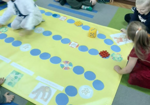 Dzieci z "Pand" grają w grę planszową "Małpki".