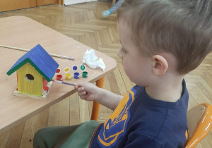 Chłopiec z gr. Małpki maluje farbami karmnik dla ptaków
