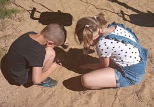Chłopiec z dziewczynką oglądają co zawiera piasek
