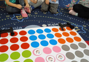Dzieci siedzą wokół maty z kolorowymi kółkami
