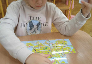 Dziewczynka układa obrazek z puzzli
