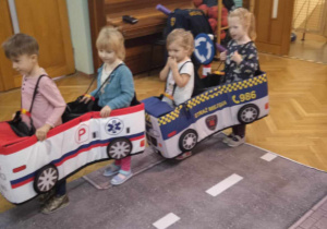 Dzieci poruszają się po ulicy autkami umocowanymi na szelkach