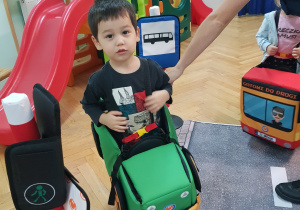 Chłopiec w zabawkowym samochodzie osobowym.