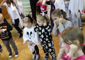 Przedszkolaki tańczą trzymając się za uszy.