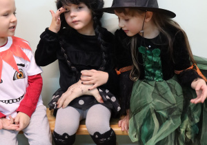 Dziewczynki w ciemnych strojach uroczych czarodziejek.