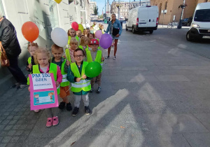 Przedszkolaki idą z balonami ulicą Piotrkowską