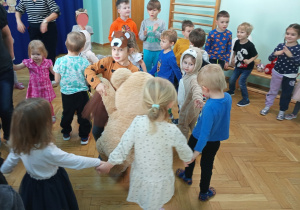 Dzieci tańczą w kole z misiami.