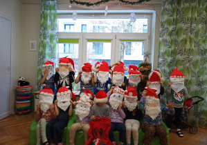 Dzieci zakryły twarze maskami Mikołajów.