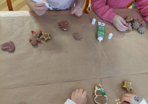 Dzieci dekorują swoje ciastka kolorowymi, cukrowymi pisakami.