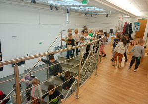 Dzieci schodzą na dół po schodach, by oglądać dalszą część wystawy.