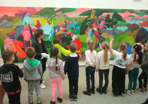 Dzieci stoją przed obrazem i opowiadają o kolorach, które im się podobają.