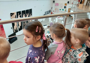 Grupa dzieci obserwuje widok na galerię z piętra.