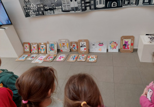 Dzieci podziwiają stworzoną przez siebie wystawę portretów.