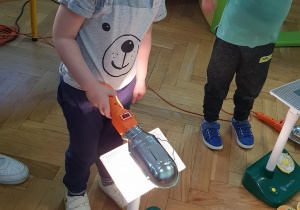 Chłopiec przykłada zapaloną lampkę do panelu fotowoltaicznego.
