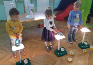 Troje dzieci przykłada zapalone lampki do paneli fotowoltaicznych.