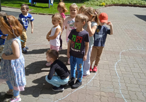 Dzieci stoją na chodniku w ogrodzie przedszkolnym w wyznaczonym miejscu
