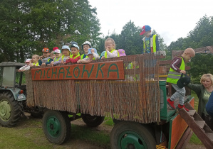 Przedszkolaki schodzą po schodkach z wozu z pomocą Pani Bożenki.