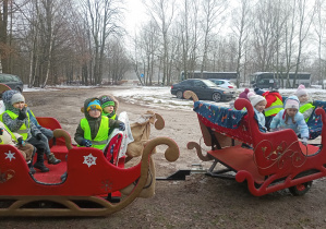 Dzieci czekają w saniach na kierowcę.