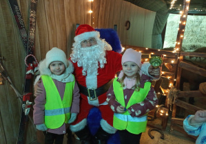 Dwie dziewczynki pozują do pamiątkowego zdjęcia z Mikołajem w Malinowym Grodzie. 2.12.2025r.