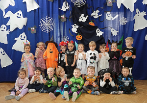 Dzieci z grupy "Żyrafki" pozują do pamiątkowego zdjęcia na tle dekoracji przed balem w dniu 31.10.2025r.