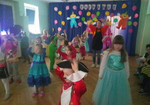 Przedszkolaki wraz z Panią Moniką wykonują różne zadania ruchowe.