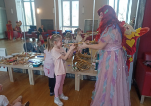 Dziewczynka próbuje wydobyć dźwięk z trąbki.