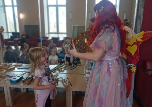 Dziewczynka słucha wskazówek jak wydobyć dźwięk z waltorni.