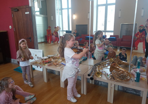 Jedna dziewczynka gra na skrzypcach a druga na talerzach.