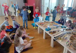 Dzieci grają na talerzach i na guiro.