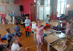 Dziewczynka gra na skrzypcach a chłopiec na talerzach.