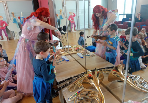 Chłopcy wydobywają dźwięki z ukulele i skrzypiec.