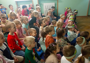 Przedszkolaki siedzą zauroczone występem iluzjonisty.