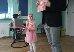 Dziewczynka z trzeciej grupy "Małpek" za pomocą kolorowych pałeczek będzie uzupełniać książkę.