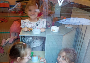 Dziewczynki podczas zabawy kuchenką - widok przez okno.