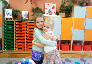 Dziewczynki po uroczystości z okazji Dnia Babci i Dziadka przytulają się do siebie.