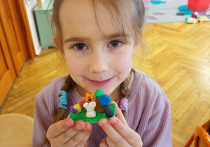 Dziewczynka prezentuje dzieła z plasteliny.