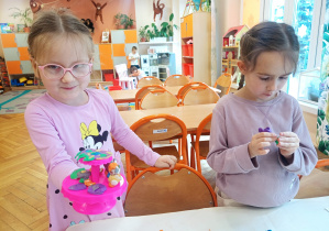 Dziewczynka pokazuje, co stworzyła, a druga wykonuje poprawki.