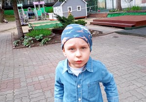 Chłopczyk o niebieskich oczach w niebieskiej koszuli i niebieskiej czapce.