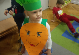 Dziewczynka prezentuje się przebrana za marchewkę.