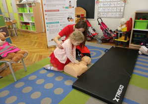 Dziewczynka wykonuje uciśnięcia klatki piersiowej na fantomie.