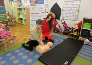 Kolejny chłopiec ćwiczy uciskanie klatki piersiowej.