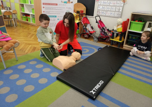 Ratowniczka czuwa nad prawidłowym ułożeniem rąk.