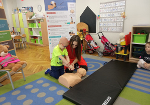 Ratowniczka pokazuje chłopcu jak powinien ułożyć ręce do uciśnięć.