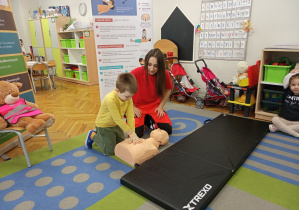 Chłopczyk ćwiczy resuscytację na fantomie.